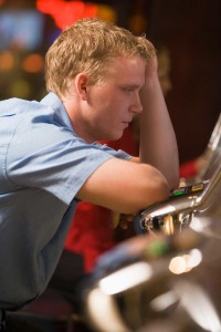 Man Leaning Over A Slot Machine Looking Sad | Michigan Abilify Lawsuit
