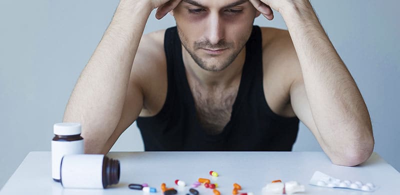 Man Looking at a Table of Pills | OxyContin Lawsuit